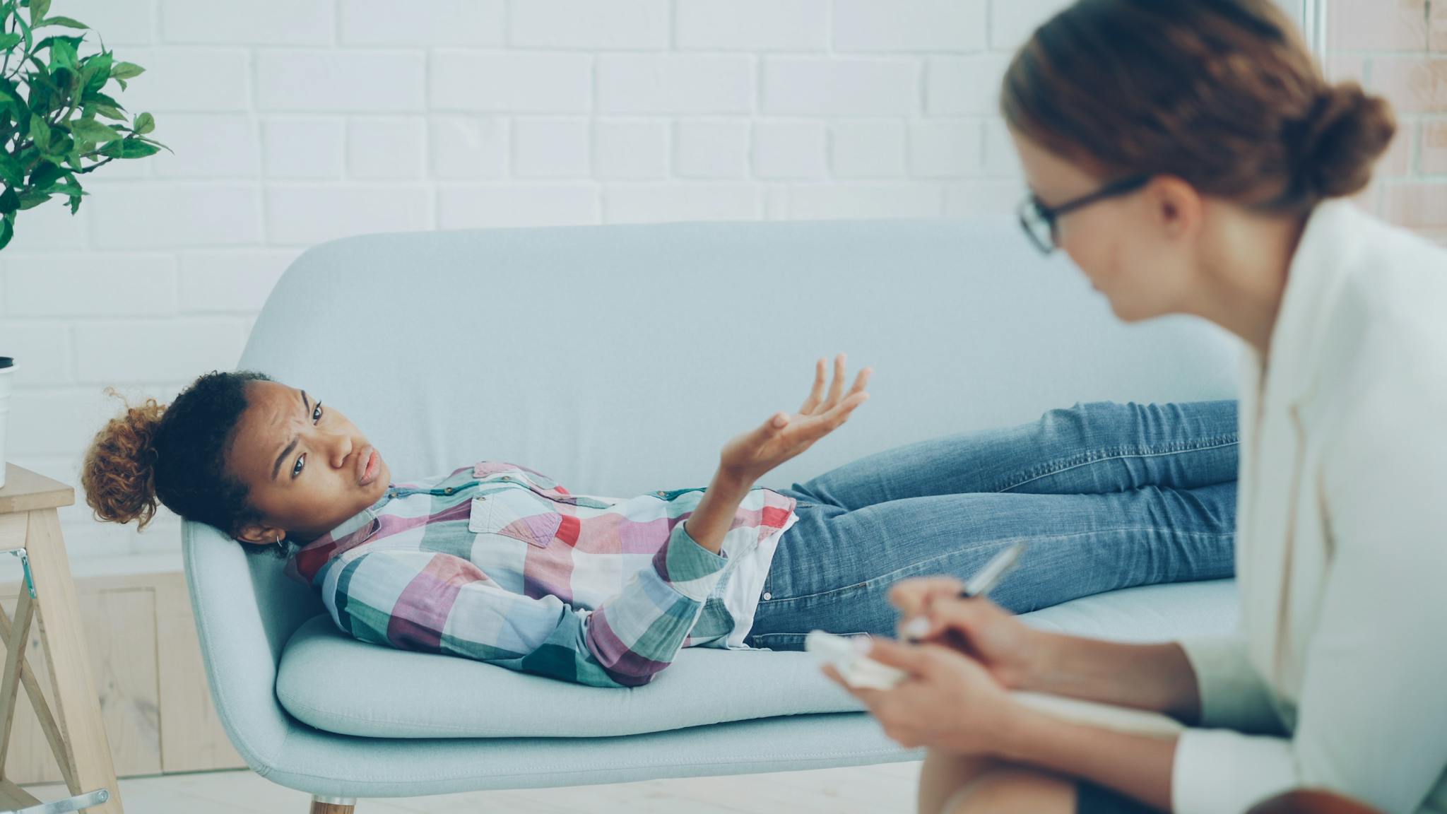 A therapy session with a psychologist and a patient on a sofa, focusing on emotional well-being.